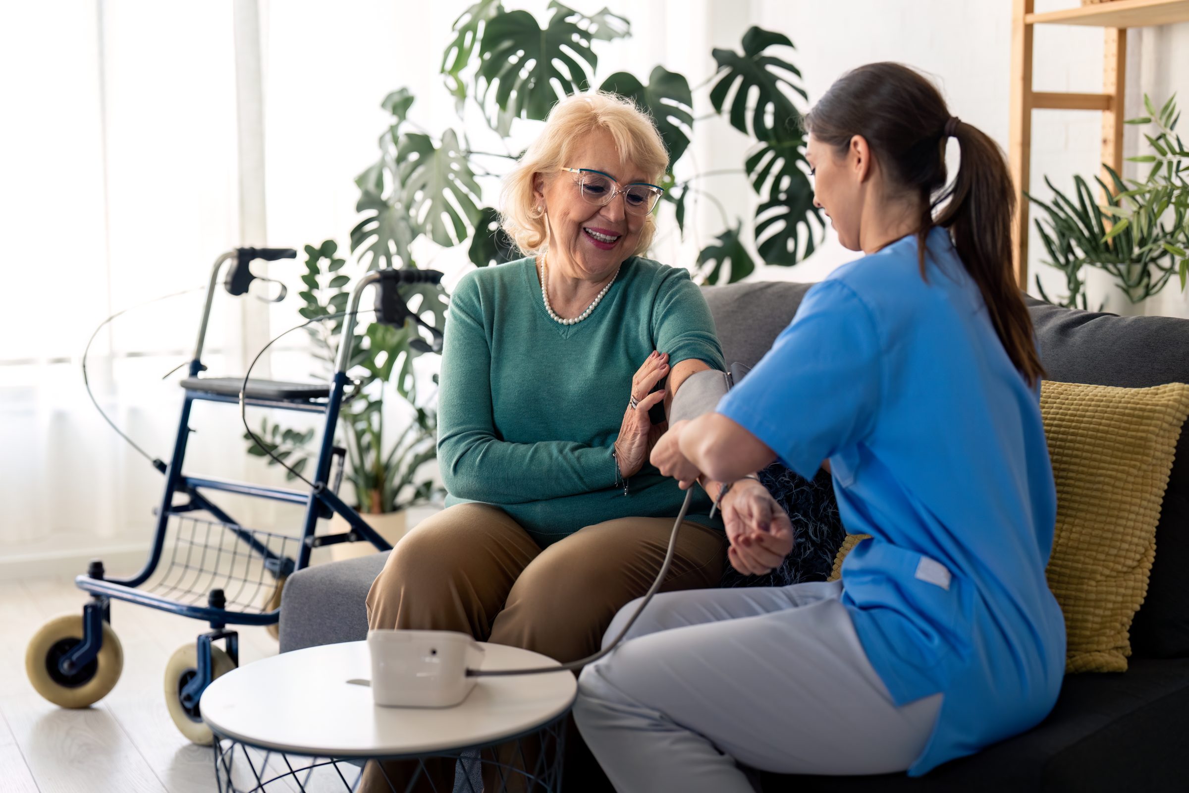 Home health nurse checking a patient's blood pressure in her living room